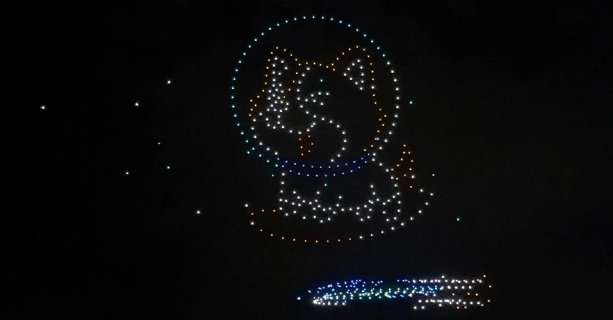 A vibrant drone display creating intricate patterns against the dark New Year's Eve sky.