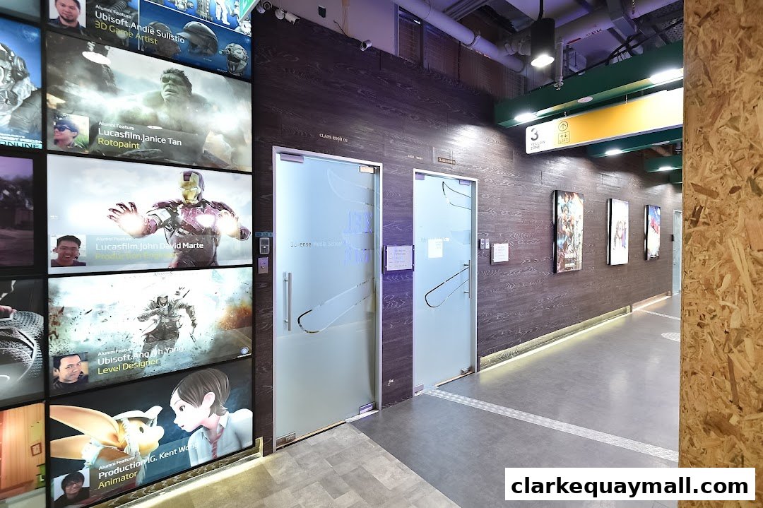 Hallway with doors and digital displays showcasing alumni work from a media school.