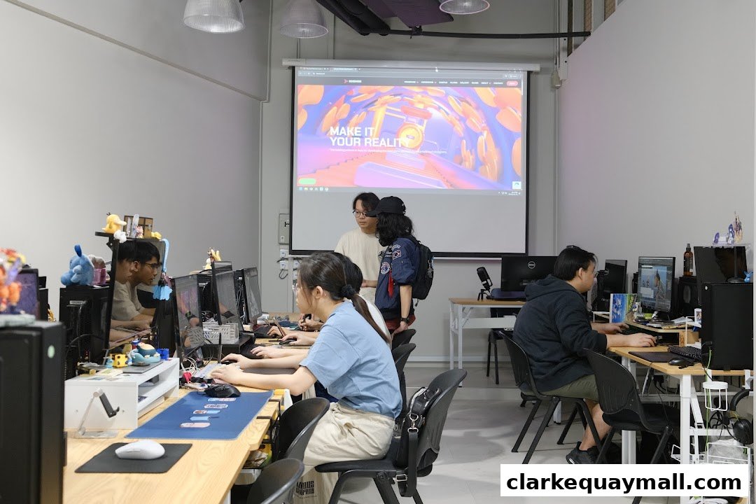 Students working on computers in a classroom with a projector screen displaying a colorful graphic.
