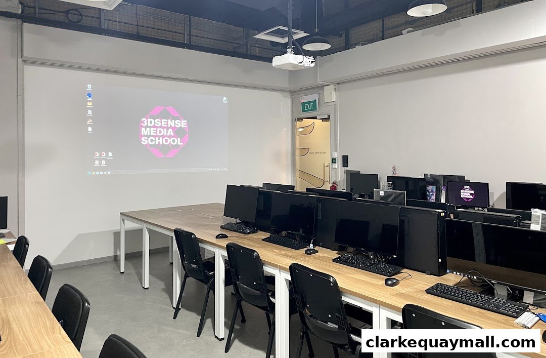 A classroom with multiple computer workstations and a projector screen displaying the school's logo.