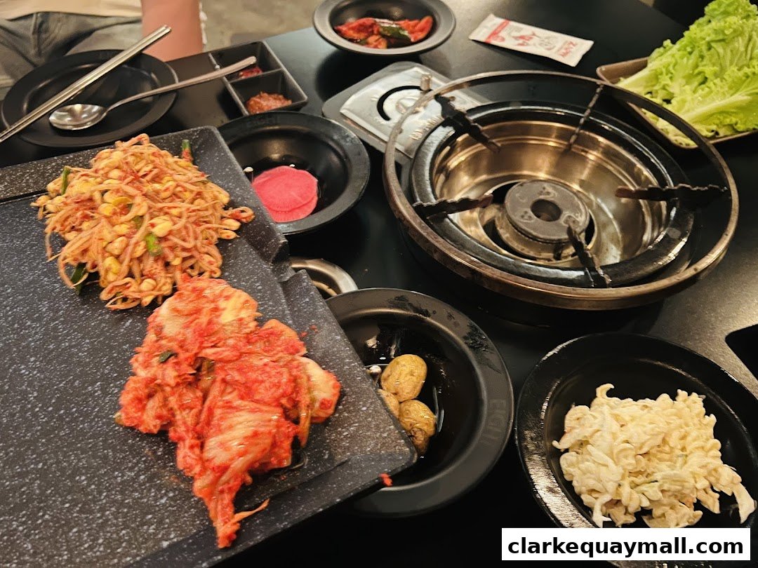 A table setting at 8 Korean BBQ with various Korean side dishes and a grill.