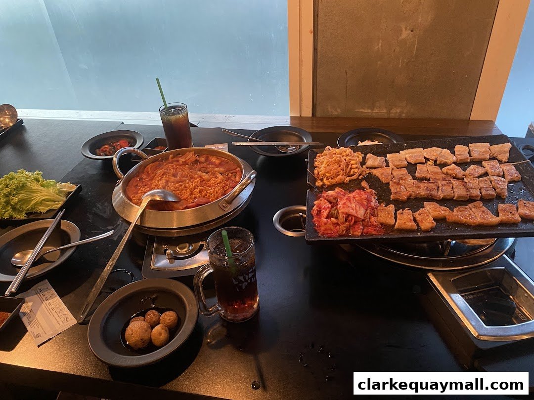 A table laden with Korean BBQ, kimchi, stew, and drinks, ready for a meal.