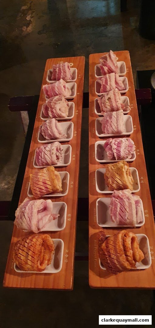 Two wooden boards display various cuts of marinated raw pork belly for Korean BBQ.