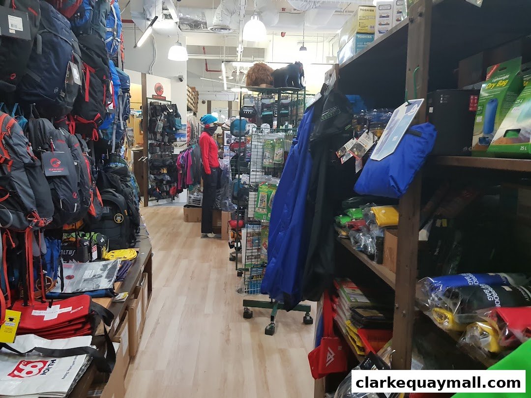 Interior view of an outdoor gear shop with backpacks, clothing, and dry bags on display.