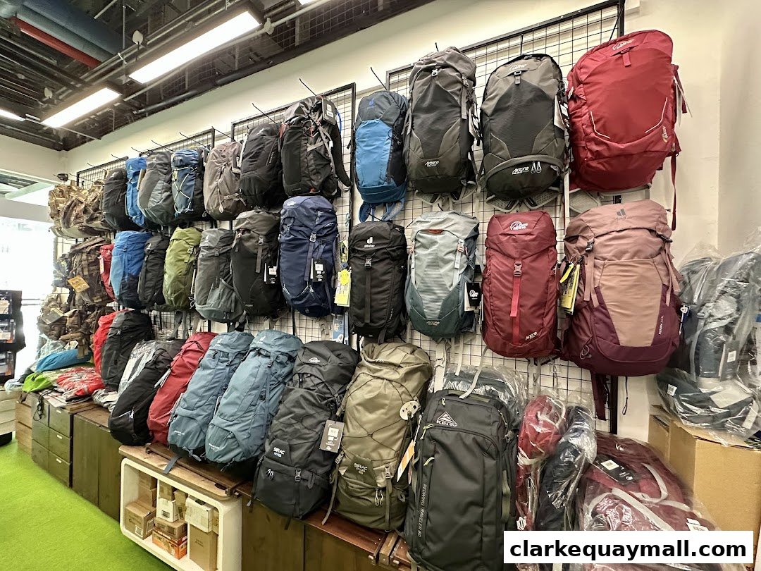 A wide selection of backpacks displayed on a wall and shelves in an outdoor gear store.