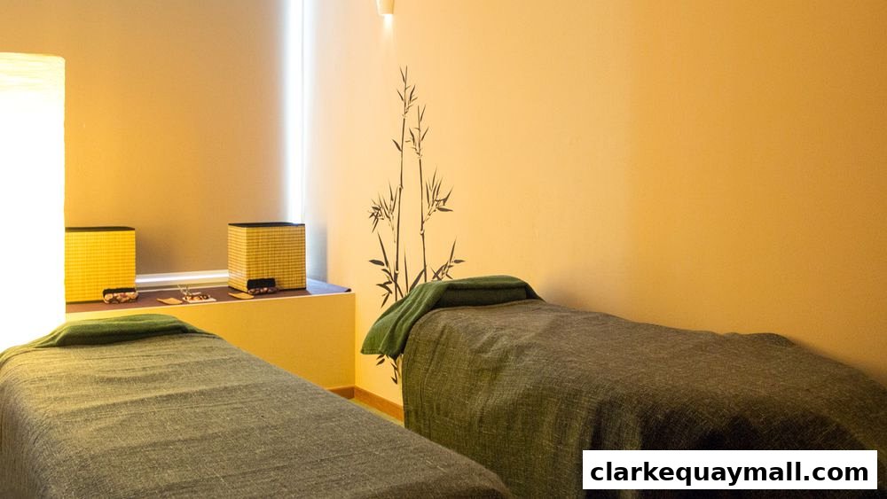 Two massage beds with green towels in a serene spa room with bamboo wall art.