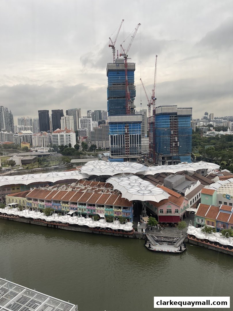 Aerial view of Clarke Quay with colorful buildings along the river and construction in the background.