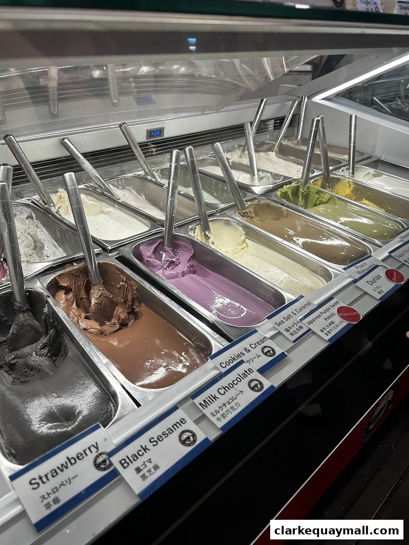 A display case filled with various flavors of gelato, including strawberry, black sesame, and milk chocolate.