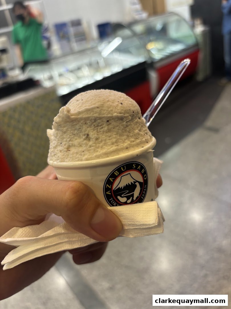 A hand holds a cup of ice cream with the Azabu Sabo logo.