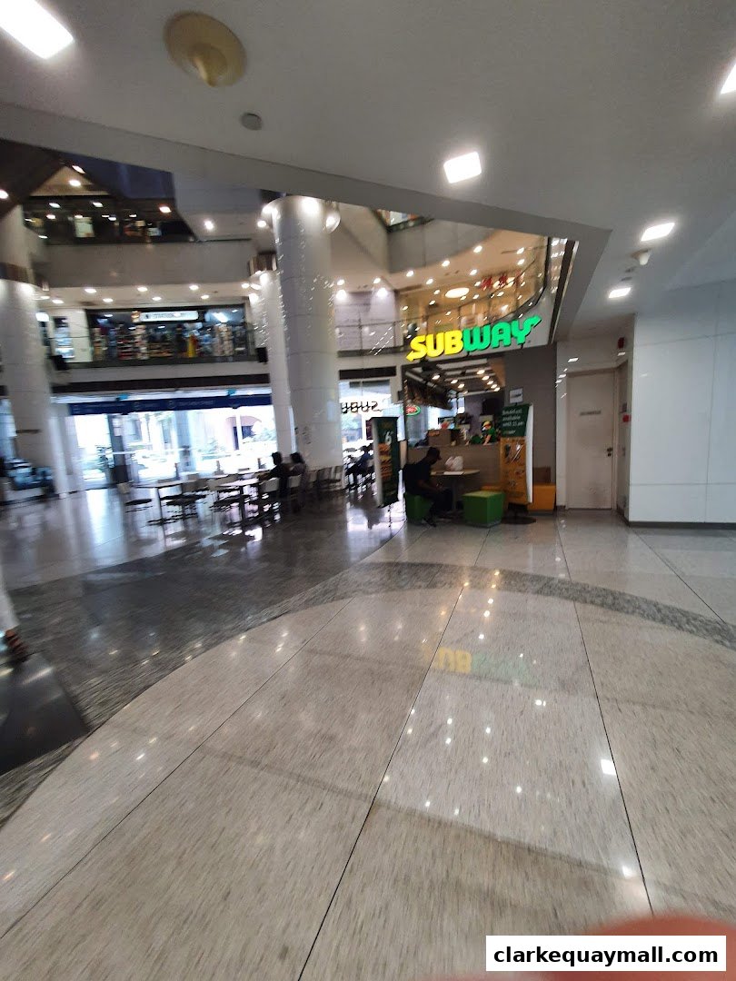 A view of the Subway restaurant entrance and seating area in a shopping mall.