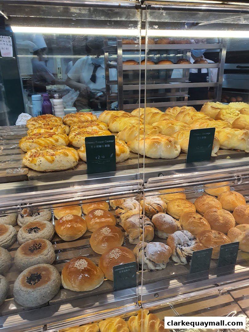 A display case filled with a variety of freshly baked breads and pastries at Barcook Bakery.