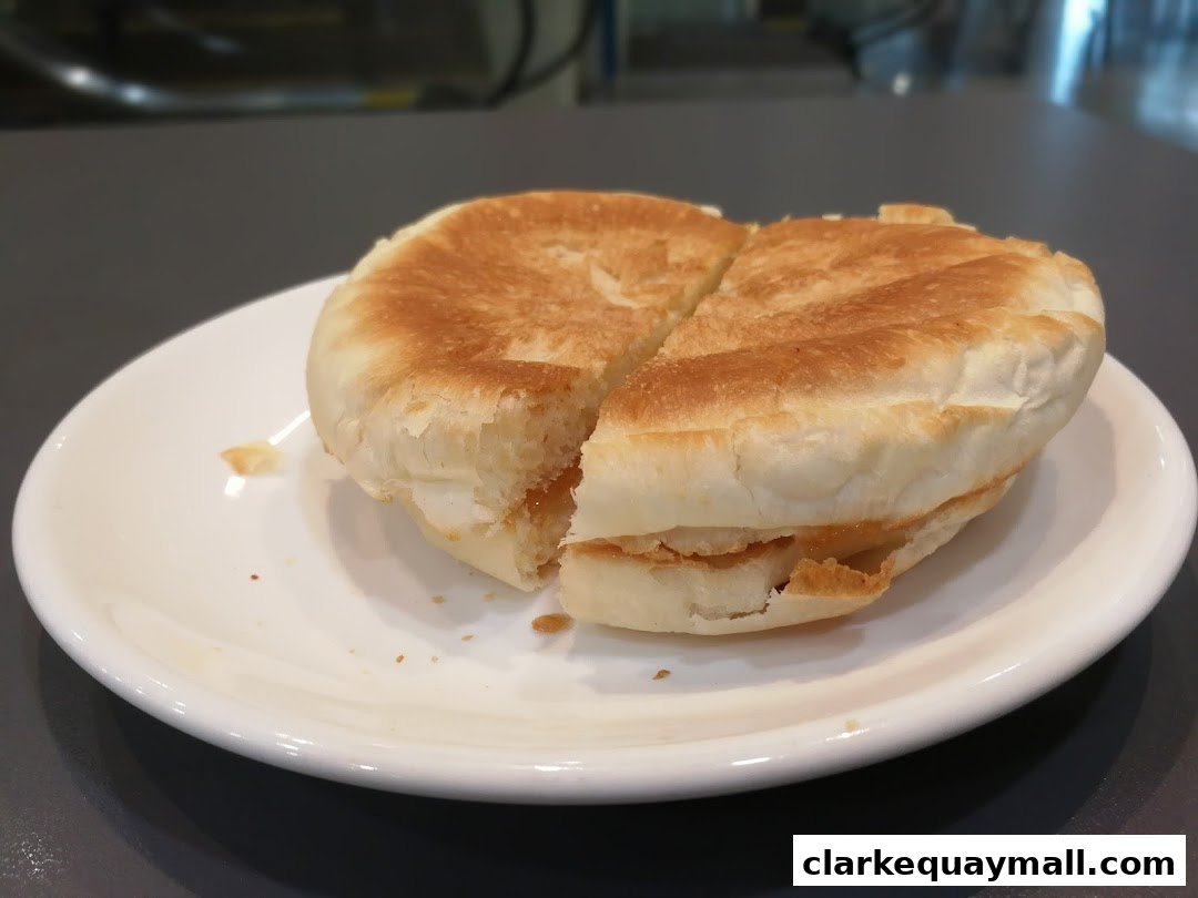 A close-up shot of a golden-brown pastry filled with a sweet filling, served on a white plate.