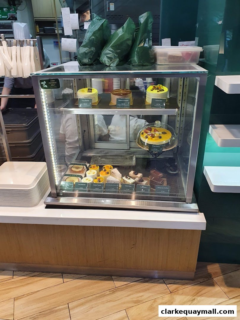 A display case filled with various cakes and pastries at Barcook Bakery.