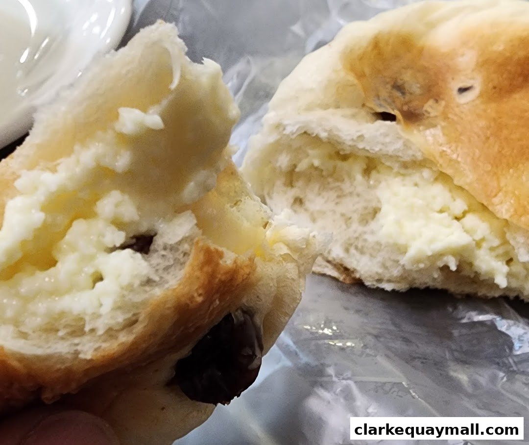 Close-up of a sweet bun filled with cream and raisins, split in half.