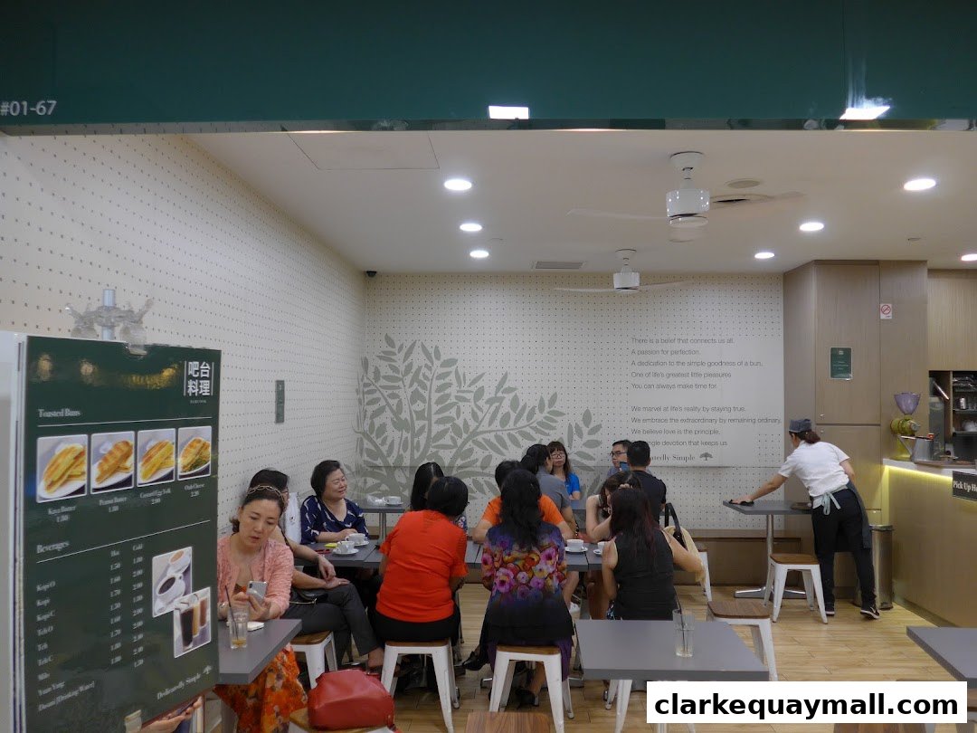 Interior of a bakery with customers seated at tables and a menu board visible.