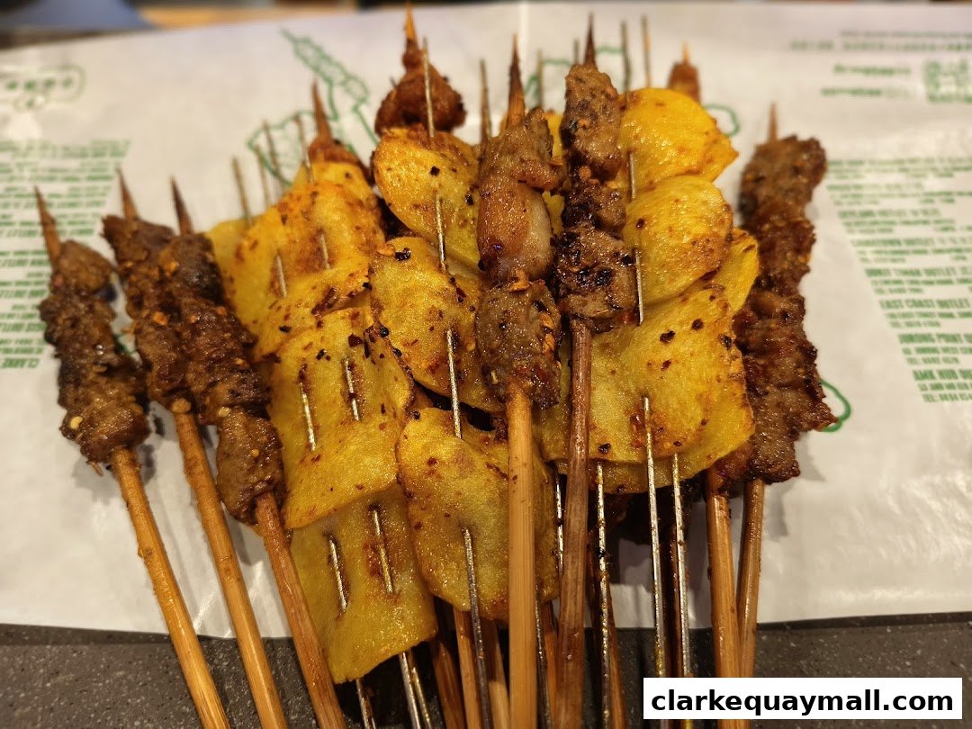A close-up shot of various skewers of grilled meat and potato slices seasoned with spices.