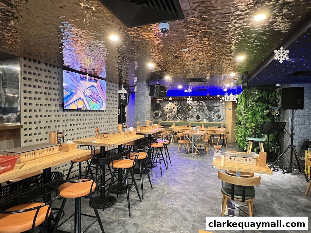 Interior view of a modern restaurant with tables, chairs, and a large screen displaying food.
