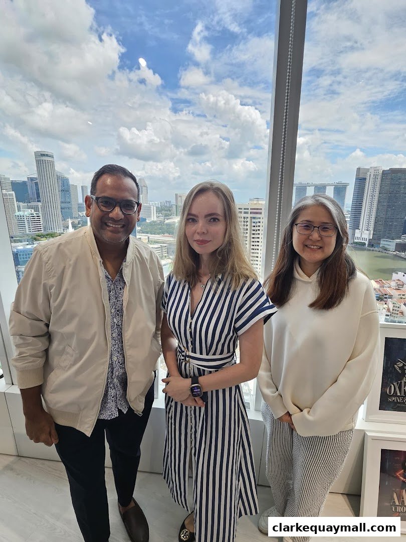 Three people smiling in front of a window with a city skyline view.
