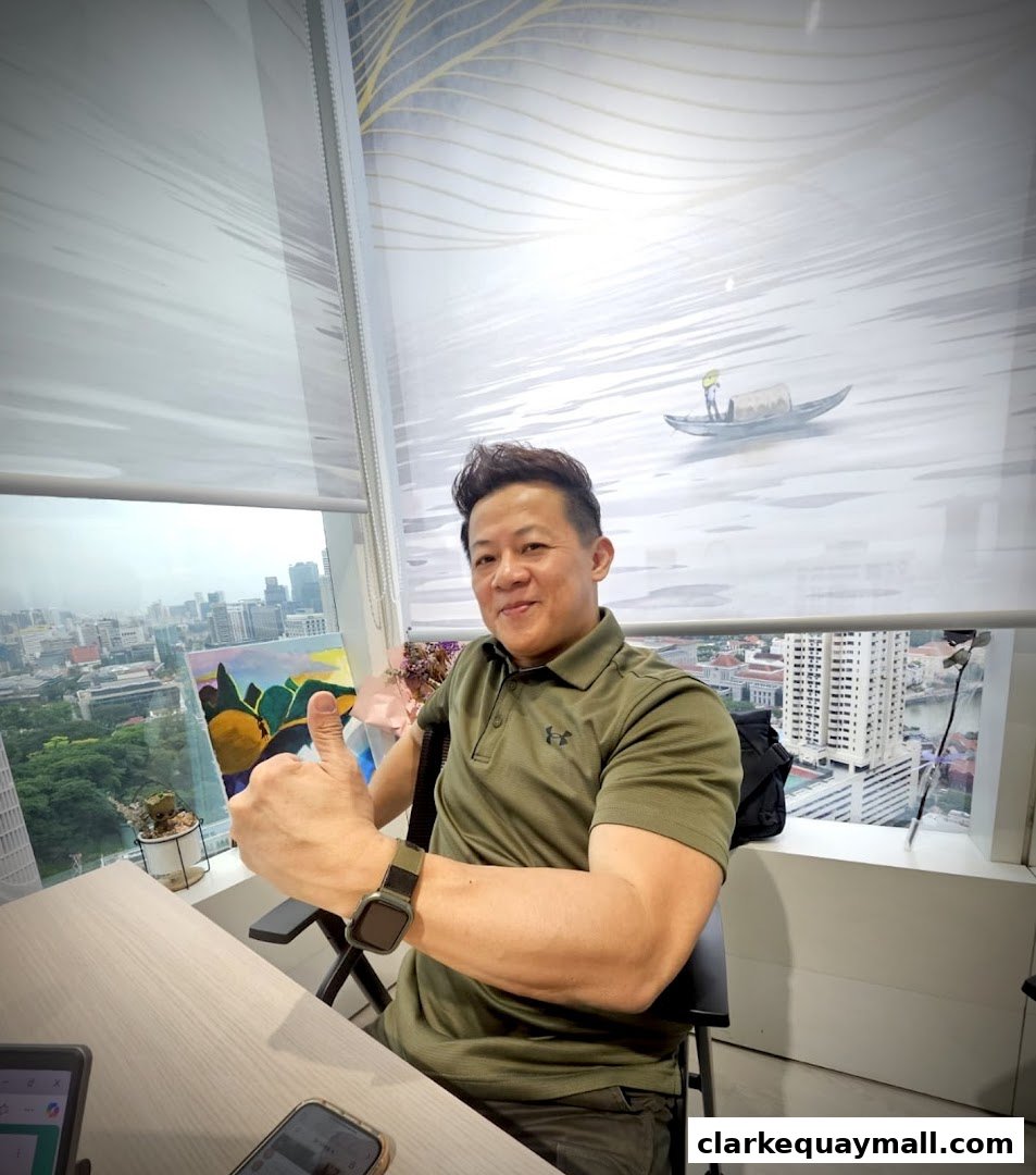 A man in a green polo shirt gives a thumbs up in front of a window with a city view.