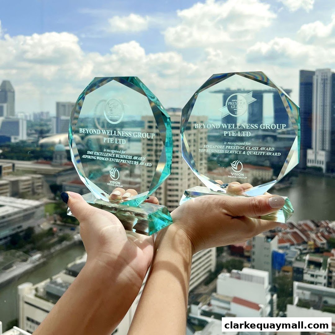 Hands holding two crystal awards with city skyline in the background.
