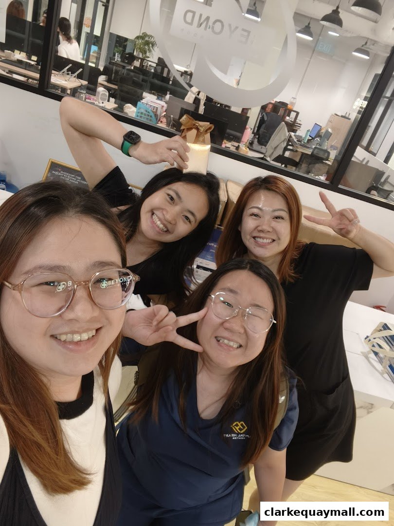 A group of smiling women posing for a selfie in an office environment.