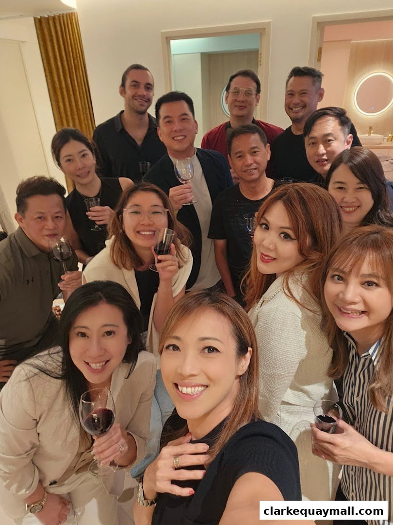 A group of smiling people holding glasses of red wine, posing for a photo.