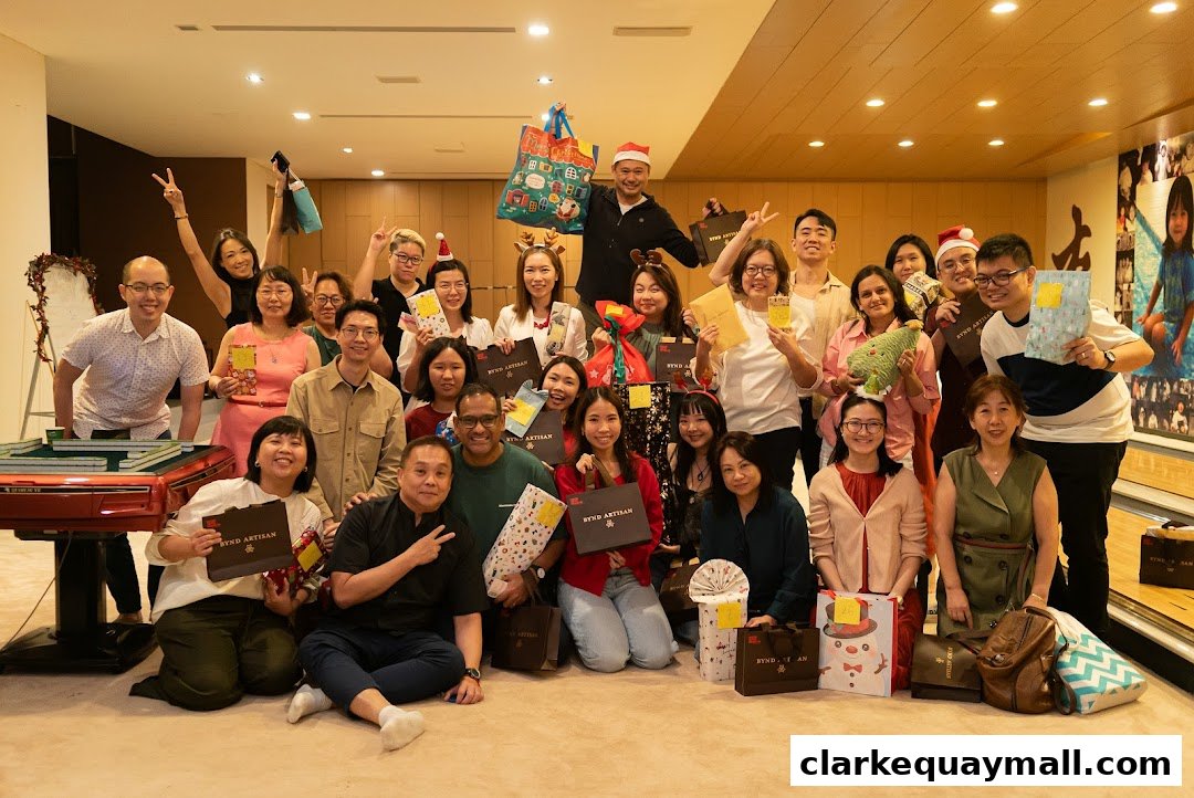 A diverse group of people posing for a photo, many holding gifts and wearing festive accessories.