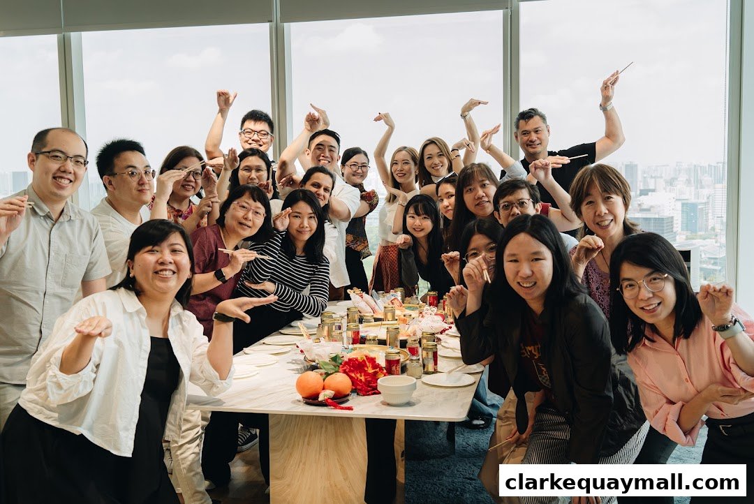 A diverse group of people posing for a photo around a table with food.