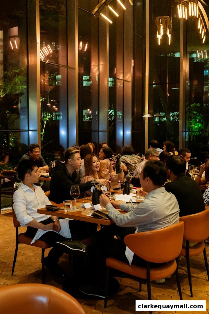 People dining at tables in a modern restaurant with large windows and stylish lighting.