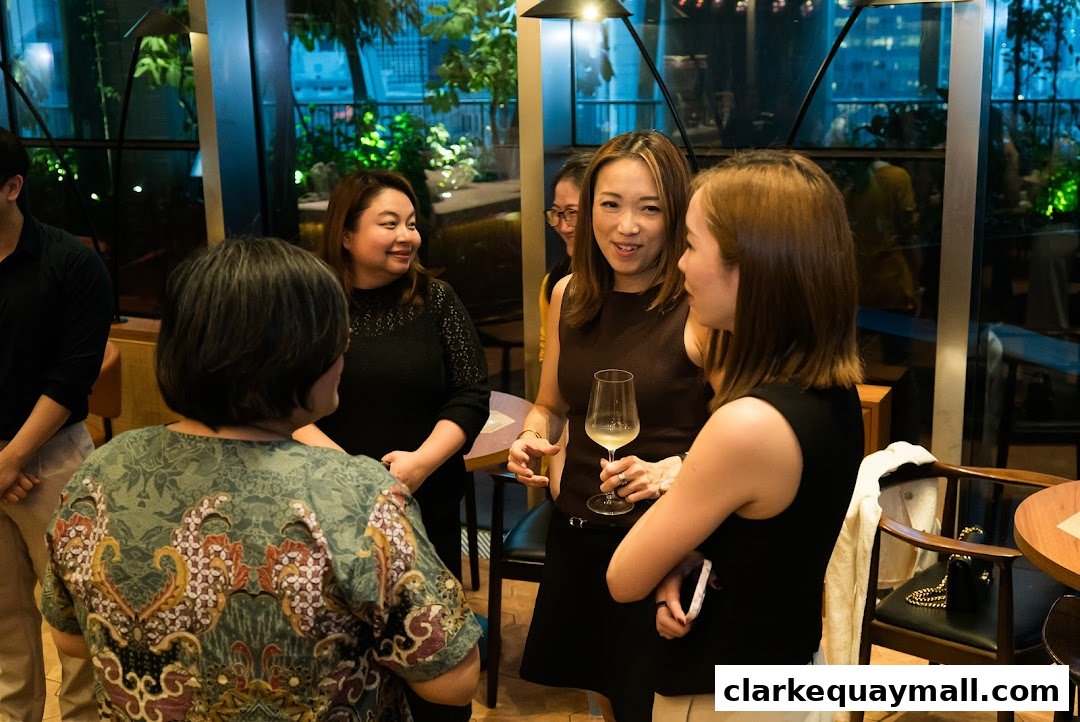 A group of people are socializing and enjoying drinks in a modern, well-lit indoor setting.