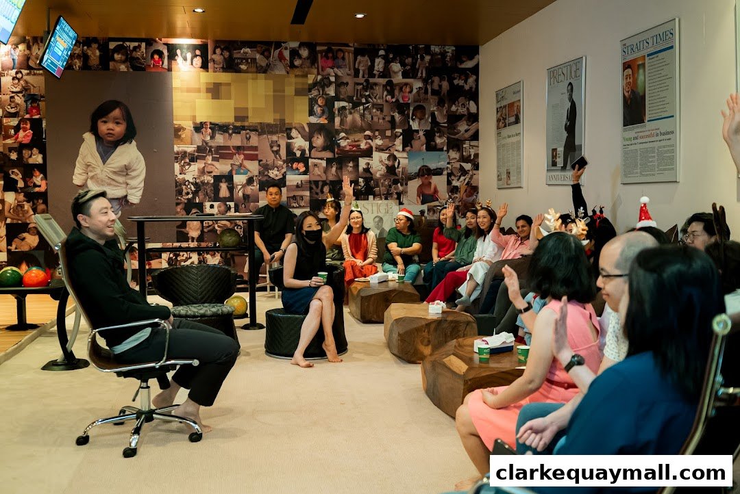 A group of people are gathered in a room, with one person in a chair and others seated on the floor.