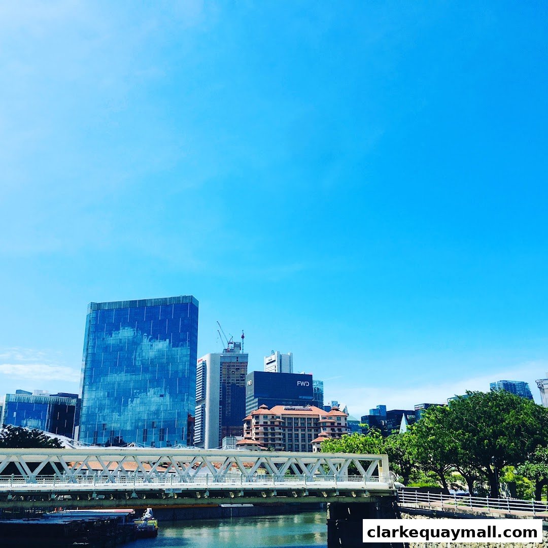 A cityscape view with a bridge over a river and modern buildings under a clear blue sky.