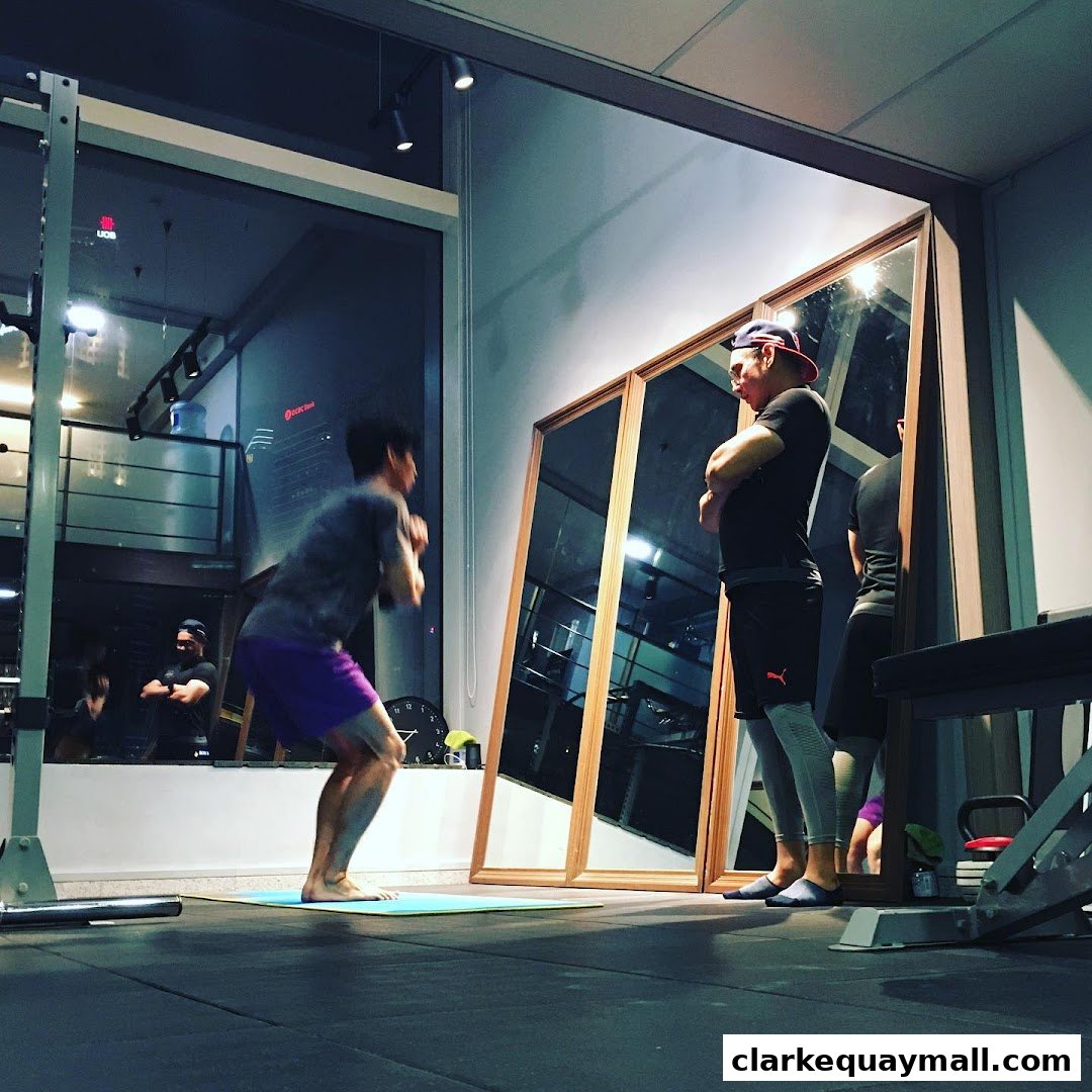 Two men are training in a gym with mirrors reflecting the workout space.