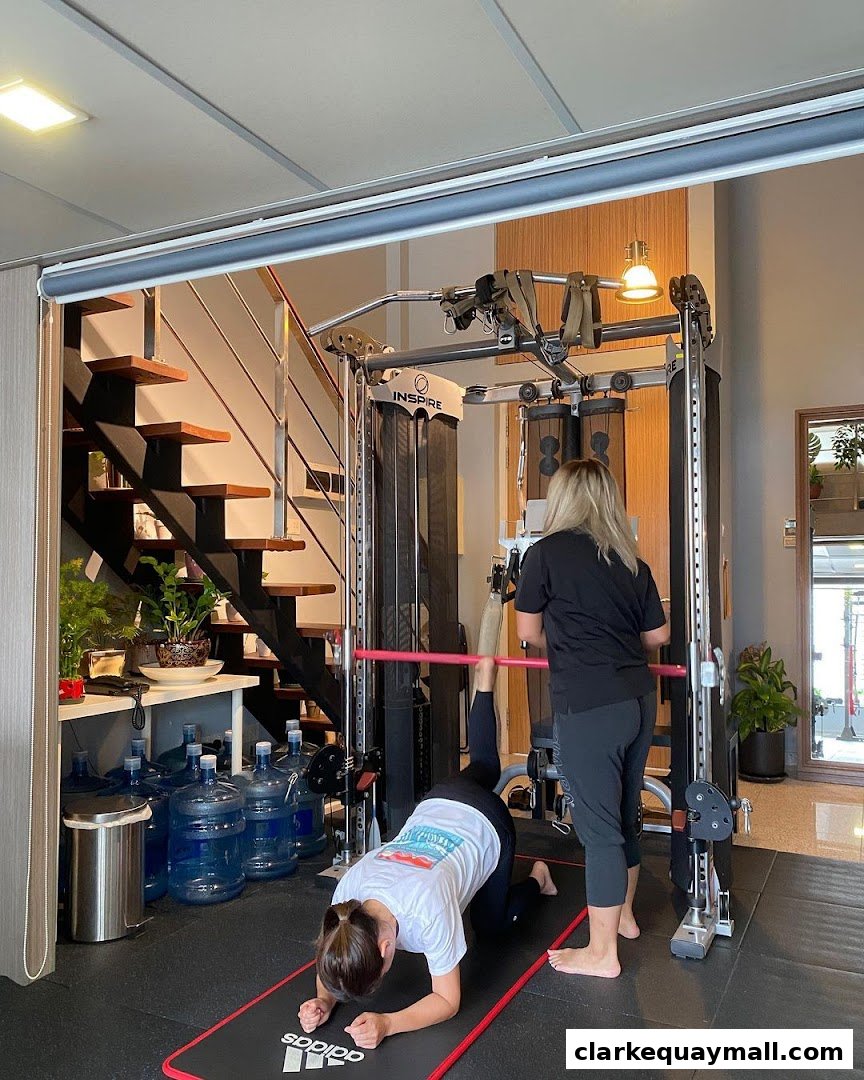 A trainer assists a client with a leg exercise using a cable machine in a gym.