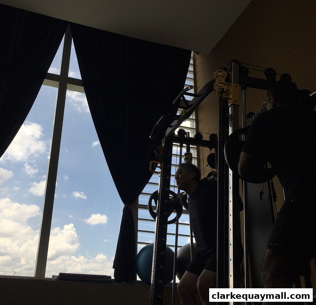 Two men are working out with weights in a gym with a large window.