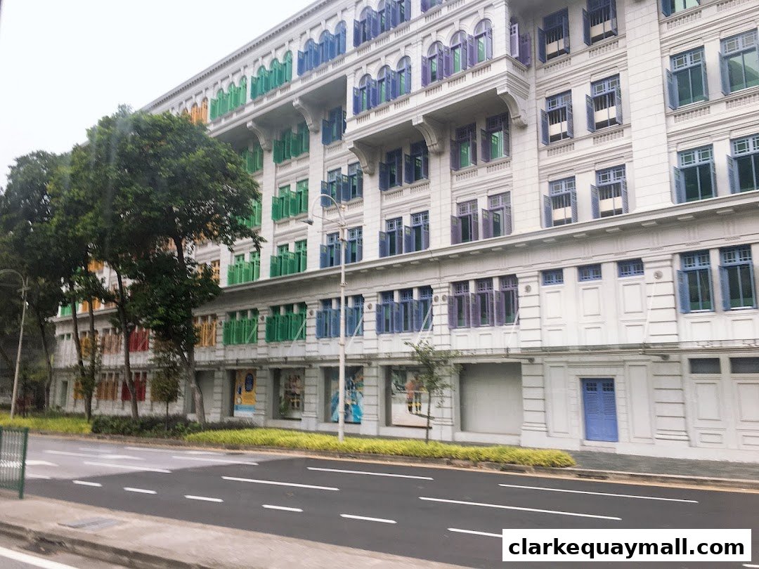 A white building with colorful windows and shutters, seen from across a street.