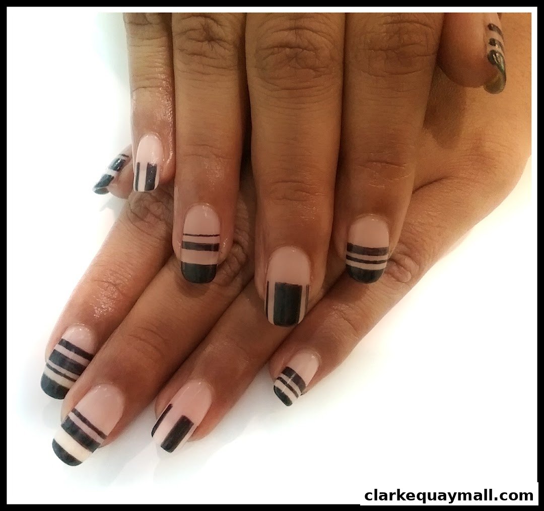 A close-up shot of hands with stylish nude and black striped nail art.