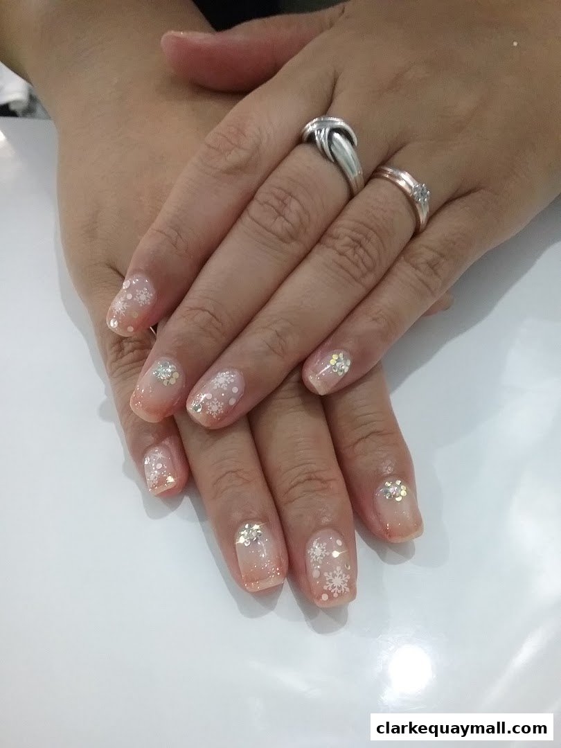 Close-up of hands with beautifully decorated nails featuring snowflake designs and glitter.