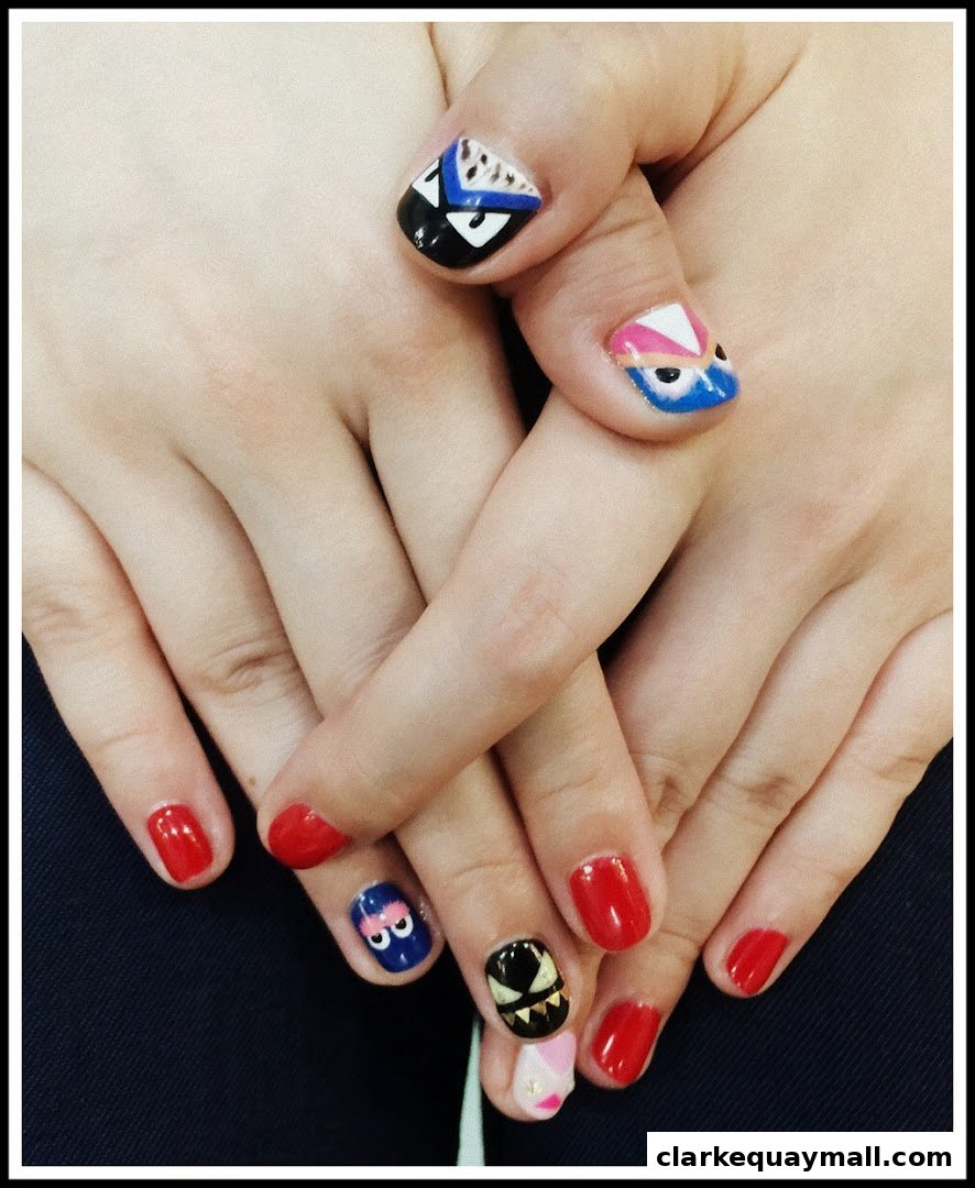 Close-up of hands with creative nail art featuring cartoon characters and solid red polish.