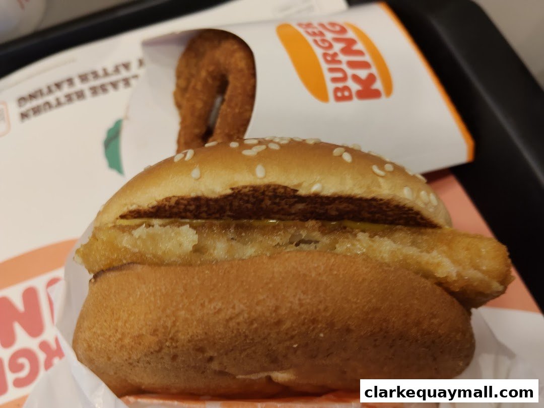 A close-up of a Burger King burger and a hash brown ring.