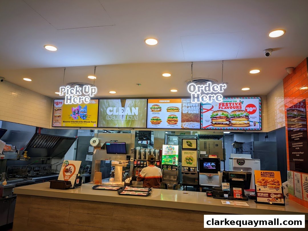 Burger King counter with digital menus displaying food and promotions, and staff preparing orders.