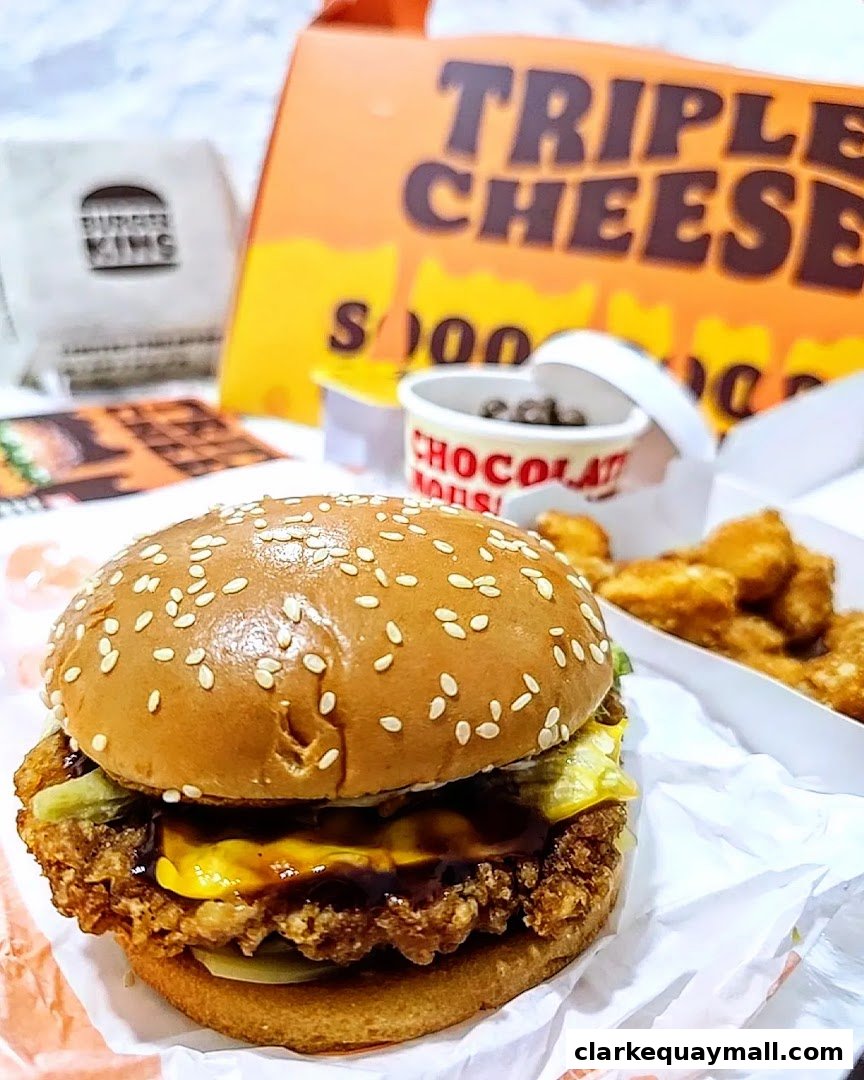 A close-up of a Burger King Triple Cheese burger with fries and a chocolate mousse.