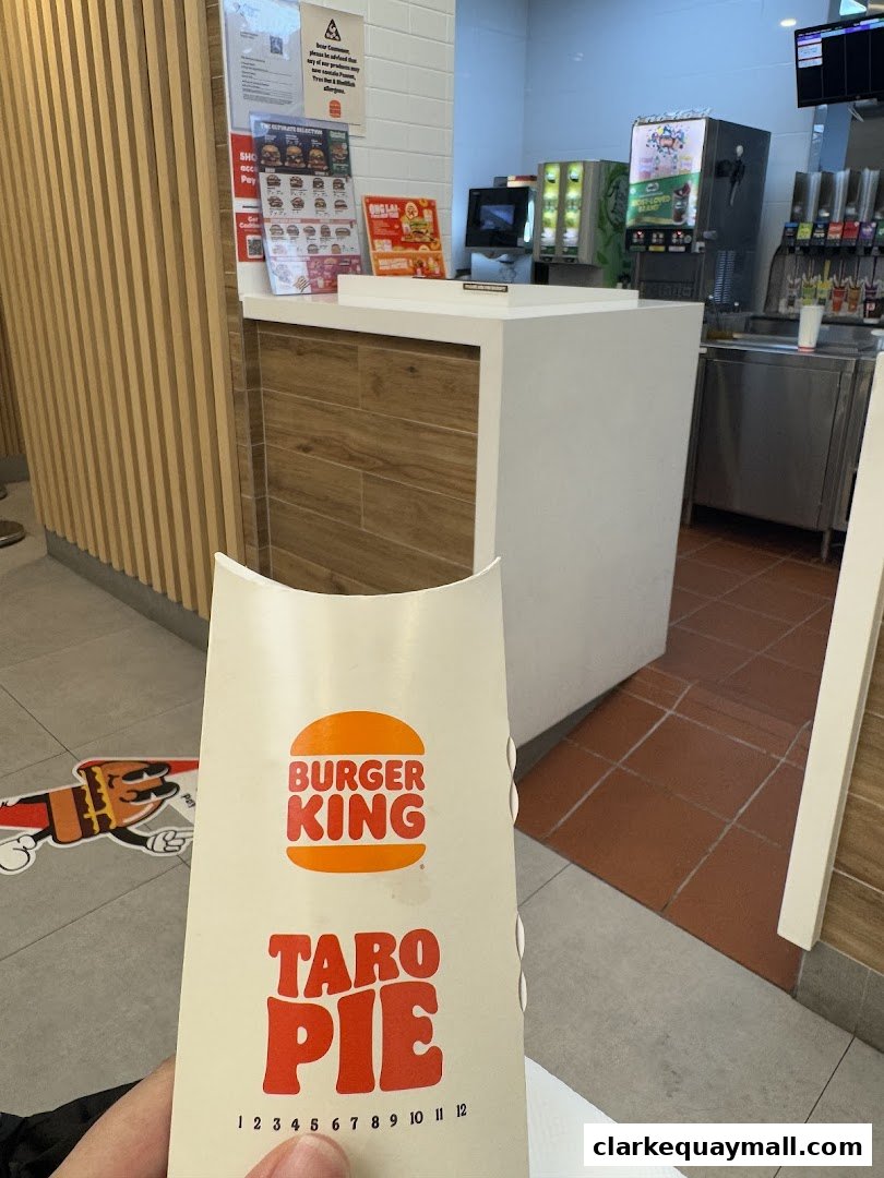 A person holds a Burger King Taro Pie box inside the restaurant, with the counter and drink station visible.