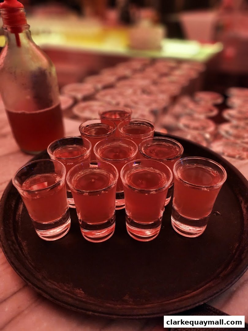 A tray of red shots with a bottle of liquid in the background.