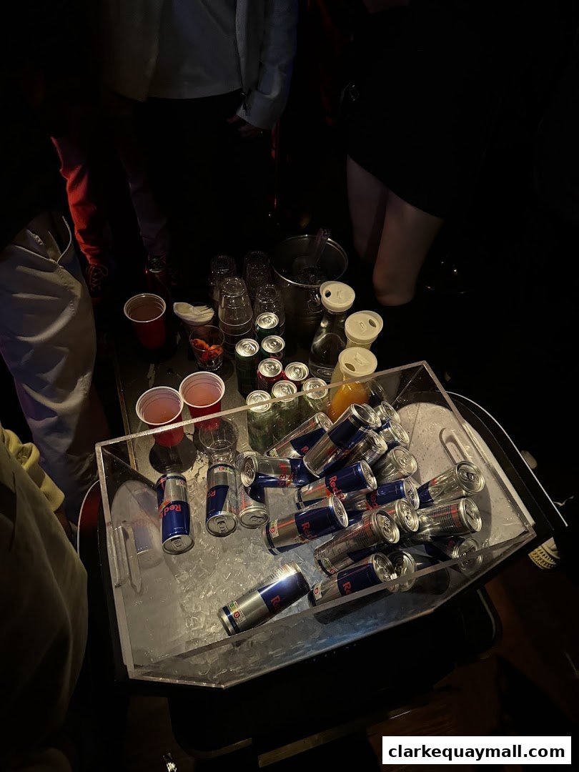 A table filled with Red Bull cans, cups, and drinks, likely at a party or club.