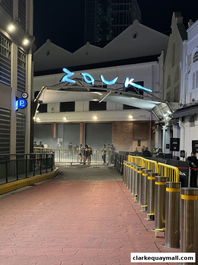 The entrance to Capital Zouk Singapore at night, with a prominent neon sign and a queue of people.