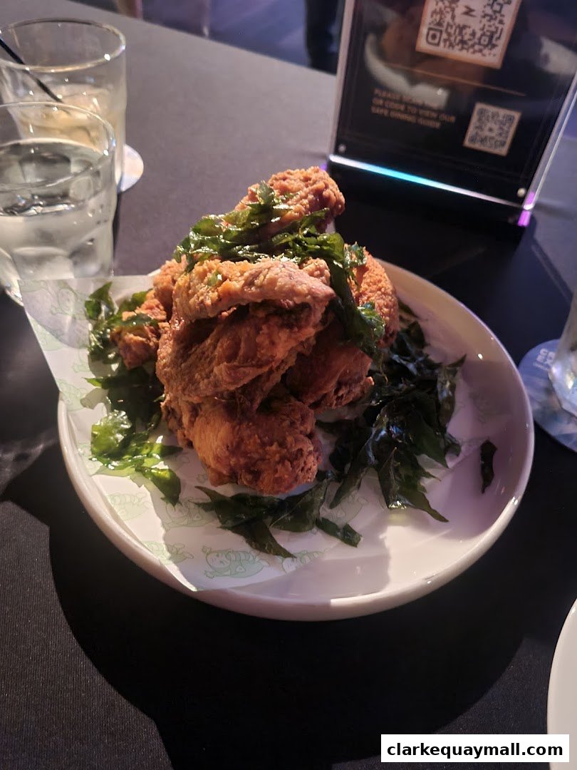A plate of crispy fried chicken wings topped with fresh green herbs.