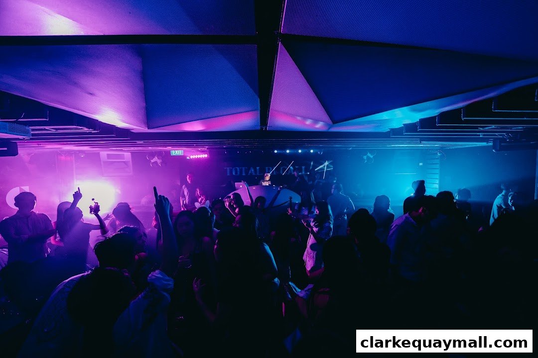 A crowded nightclub with people dancing under purple and blue lights.