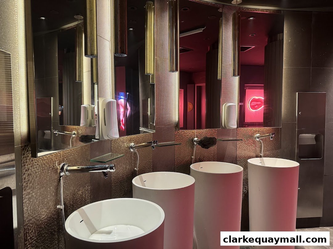 Modern bathroom with multiple sinks, mirrors, and a neon lip sign.
