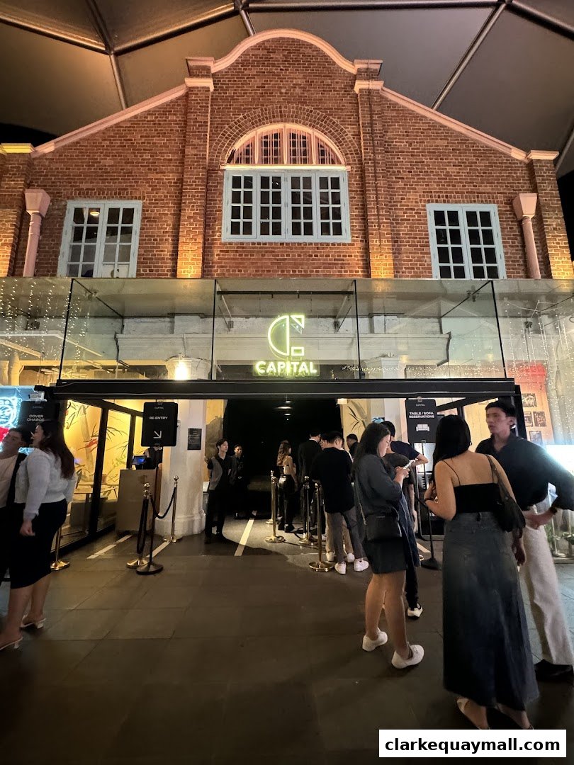 People queuing outside Capital Zouk Singapore, a venue with a brick facade and illuminated signage.